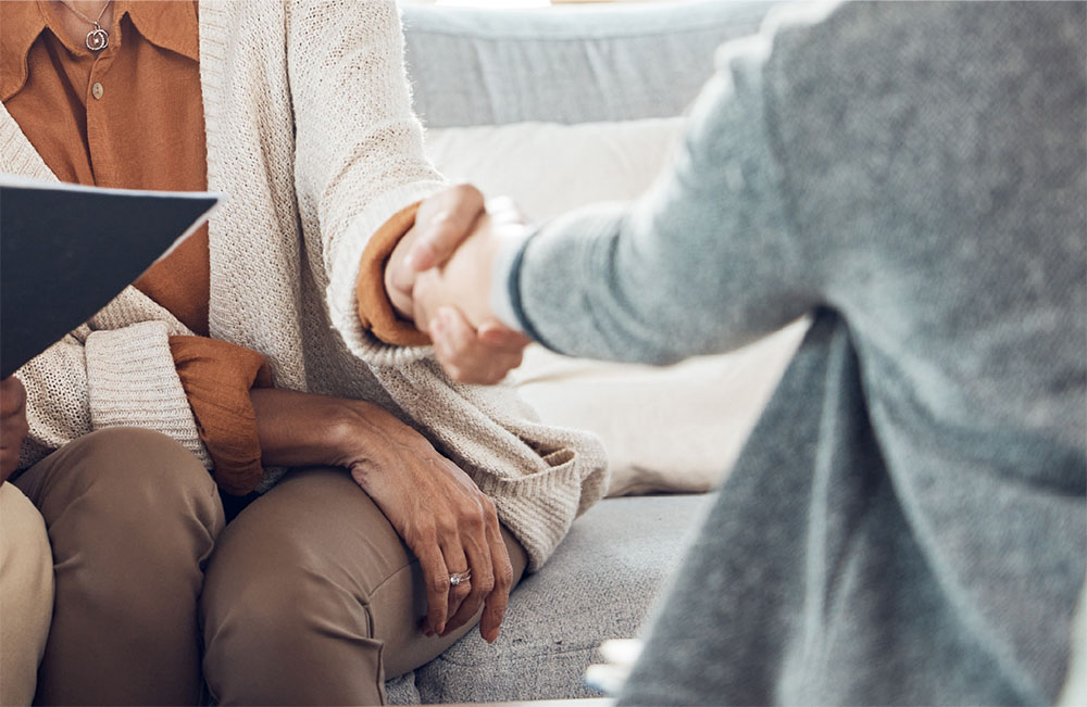 2 people sitting down shaking hands