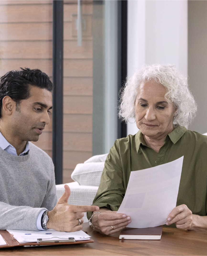 Advisor speaking with a woman in her 70s and looking over a document.