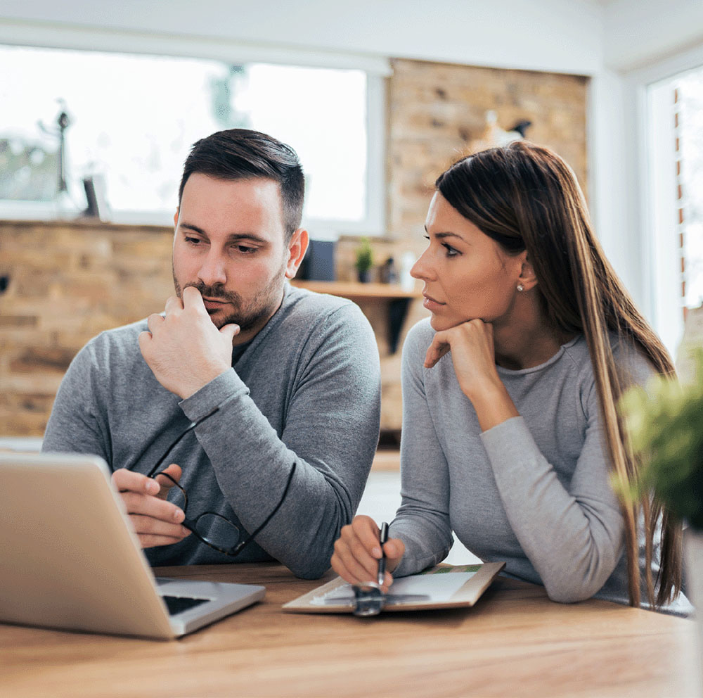 Man and woman sitting at a desk looking at a computer.