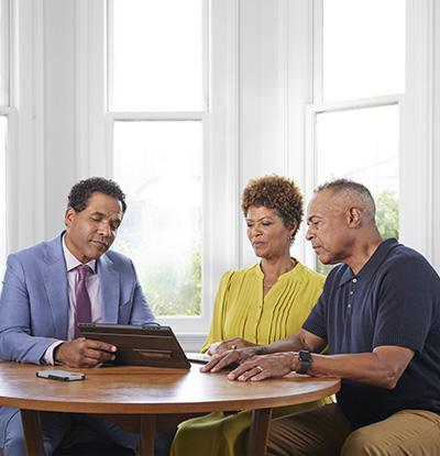 financial professional and a couple sitting at a desk and talking.