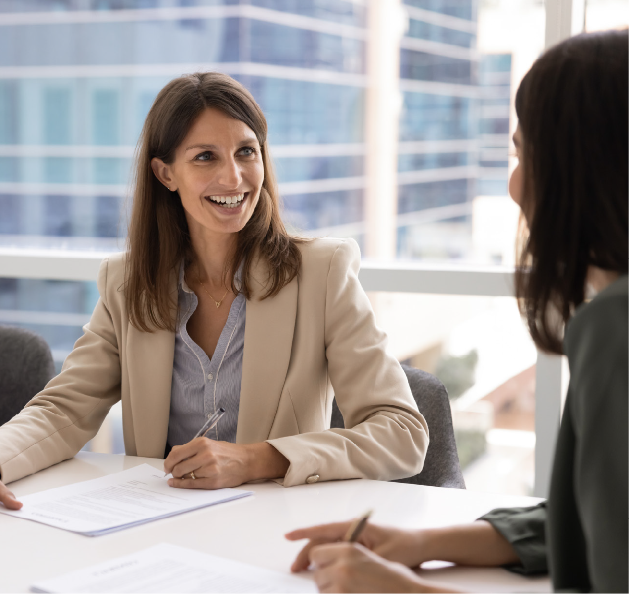 2 women talking while sitting at a desk in an office