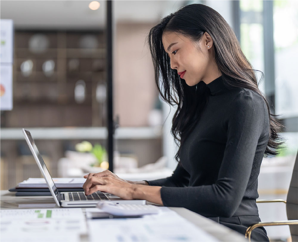 Woman sitting at desk and looking at her laptop.