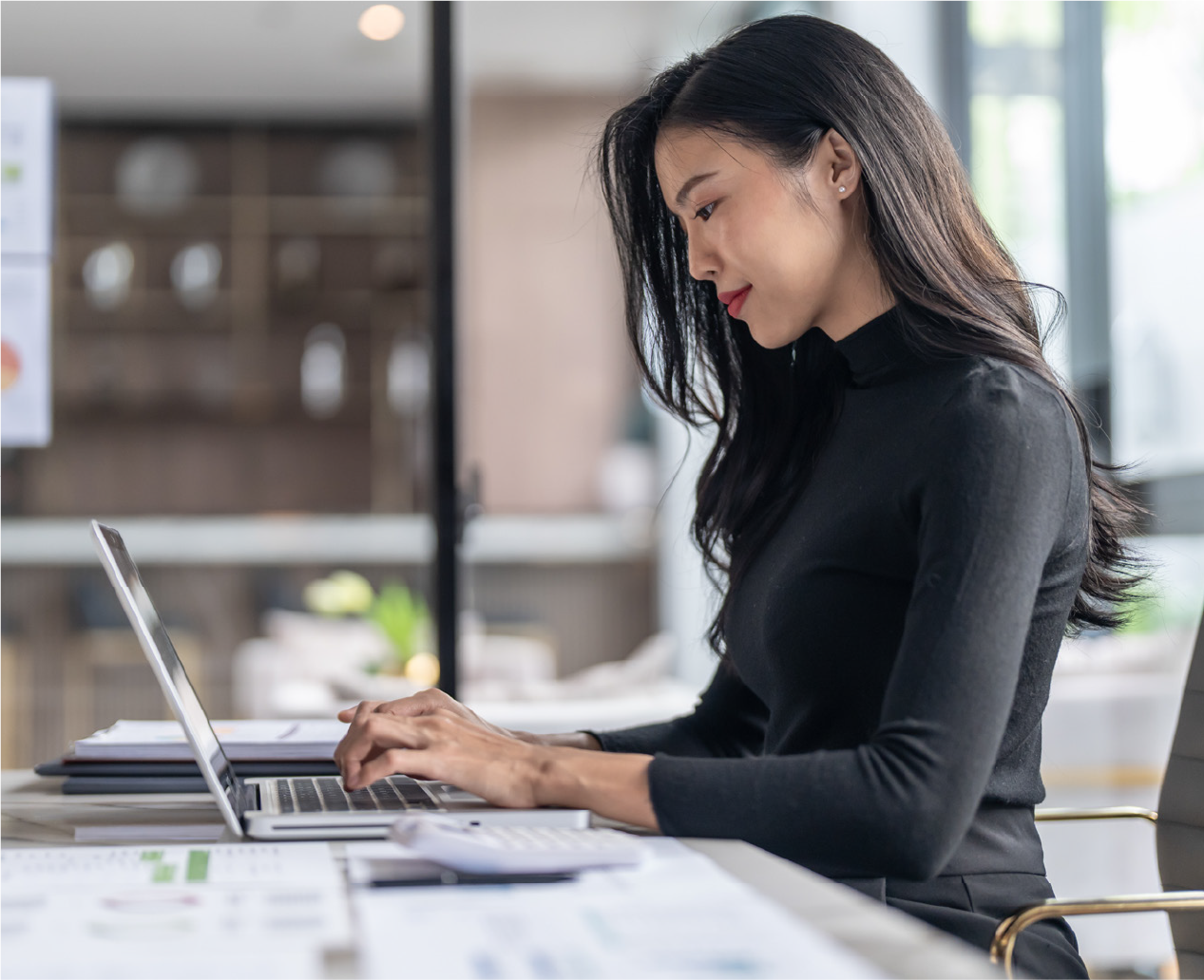 Woman sitting at desk and looking at her laptop.