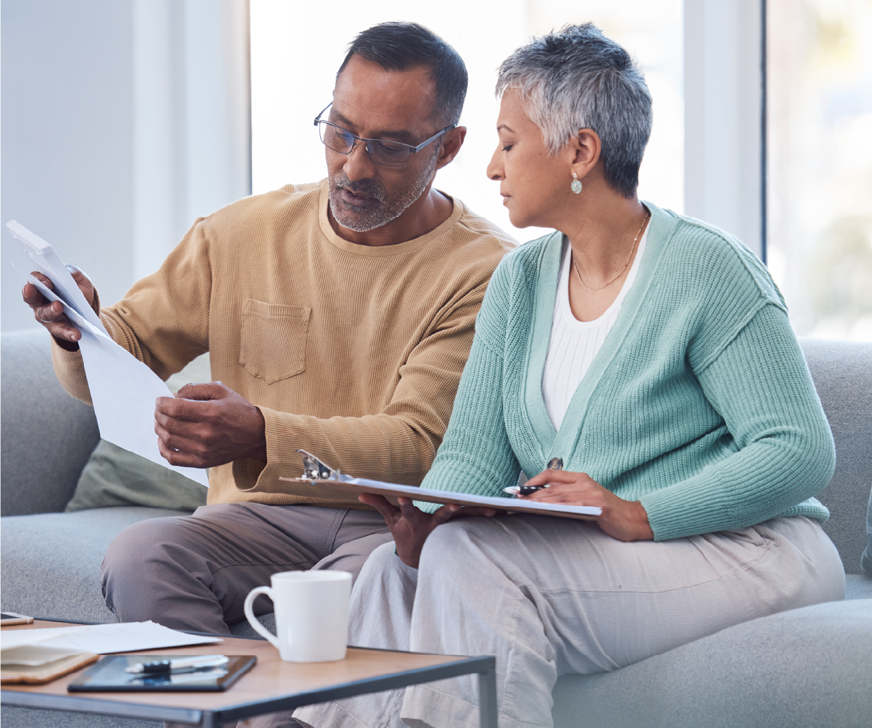 Man and woman sitting on a couch and looking over documents.