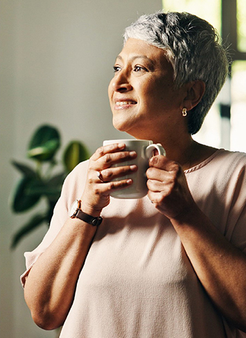 Woman holding a coffee cup and smiling.