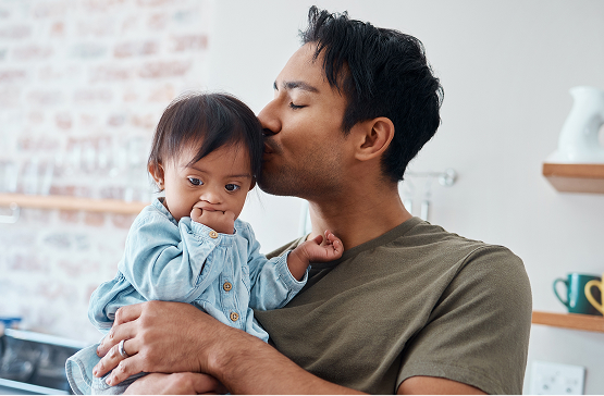 A caregiver holds a child with special needs in a cozy kitchen, highlighting the importance of financial planning for families supporting dependents with lifelong care needs.