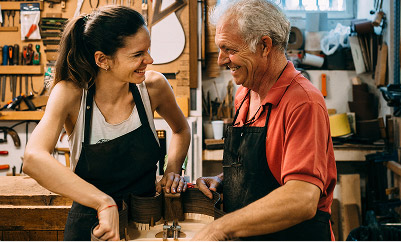 A father and daughter working together on a woodworking project in their family-owned workshop, surrounded by tools and equipment