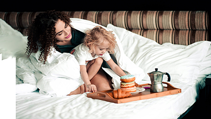 woman and child on bed, eating breakfast