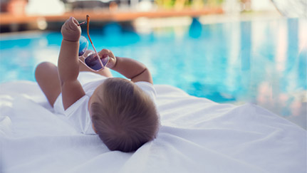 infant on a towel near a pool