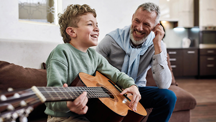 man with little boy playing guitar