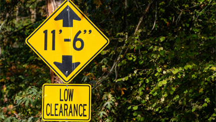 Yellow low-clearance warning sign indicating 11-foot-6-inch vertical clearance.