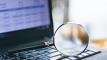 magnifying glass resting on a laptop keyboard.