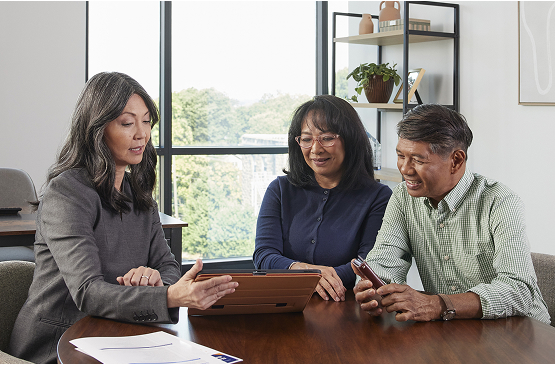 Three people sitting at a table looking at information on a computer