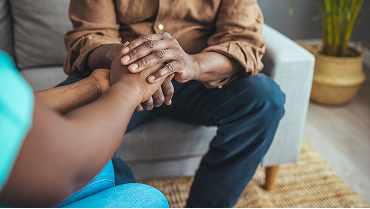 A tight shot of a caregiver daughter lovingly holding her father's hands.