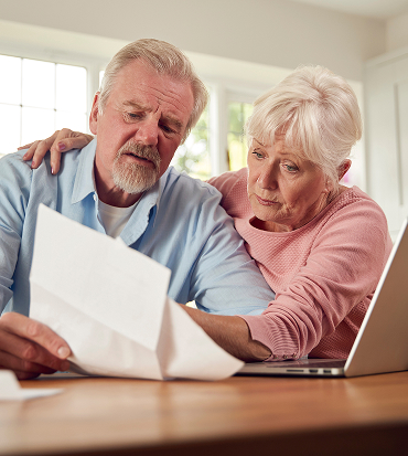 The couple is leaning close together at a kitchen table, appearing focused and engaged as they review paperwork.