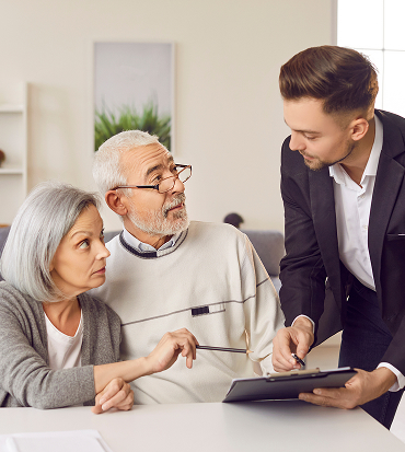 An elderly couple consults with a financial professional in their living room, discussing strategies to manage unexpected expenses in retirement.