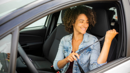 A teen girl buckling up in a car.  
