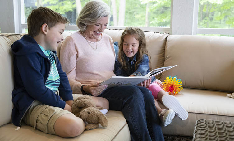 Older woman reading a book to young boy and girl