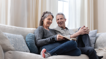 man and woman sitting on couch looking at retirement materials
