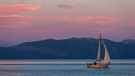 Sailboat on water in front of lake at sunset